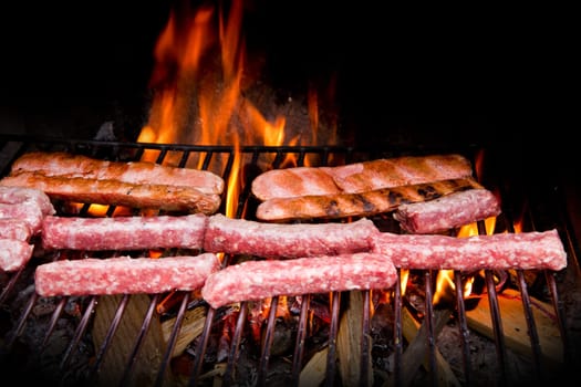 Brats  cooking on the grill with a flame in the background