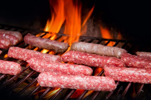 Brats  cooking on the grill with a flame in the background