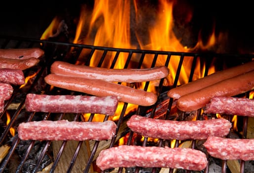 Brats  cooking on the grill with a flame in the background