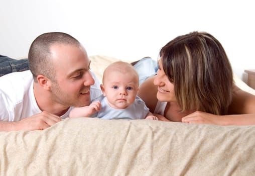 mom dad and the new born baby lying on the bed