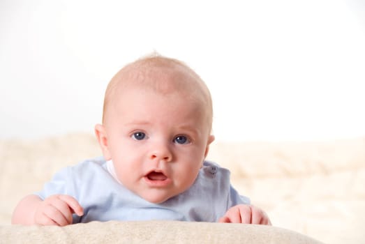talking baby with blue eyes ona bed