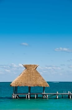 Tiki Hut on dock with blue ocean and sky