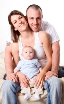 mom dad and the new born baby sitting on the bed