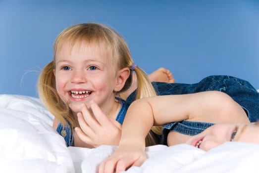 two kids playing in a bed on blue
