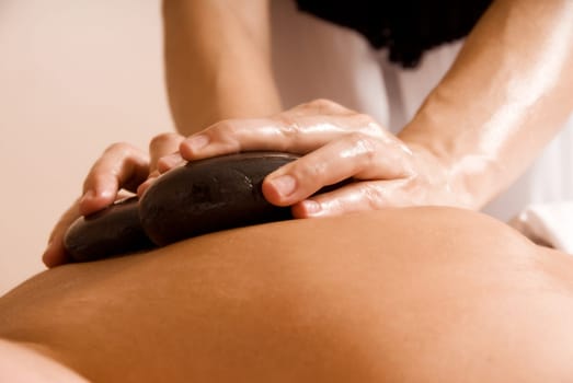 young woman getting a stone massage at a spa