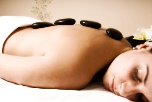 girl getting hot stone massage in day spa