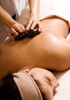 young woman getting a stone massage at a spa