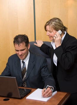 man and woman in a room with a laptop writing on paper