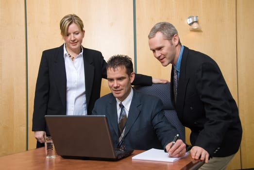 3 business people around a laptop in a meeting