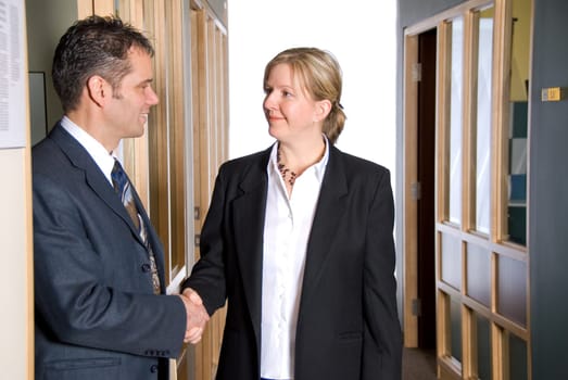 two business people shaking hands in the hallway