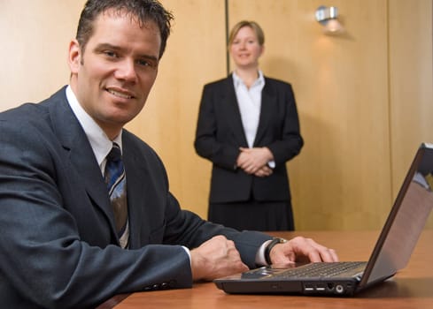 2 people looking at the camera with a laptop