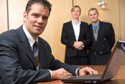 3 people looking at the camera with a laptop