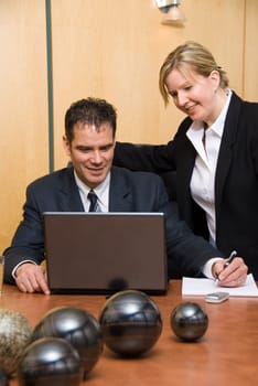 man and woman in a room with a laptop writing on paper