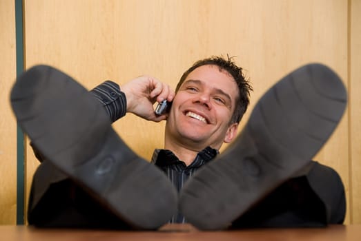 business man with his feet on the desk on the phone