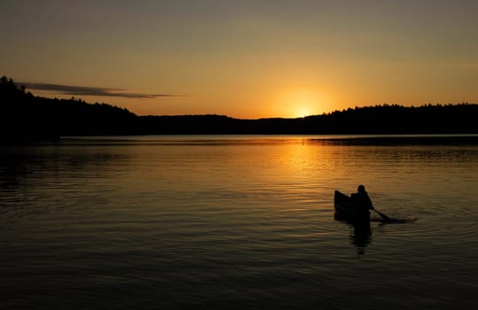 canoe on lake with sunset in silhouette