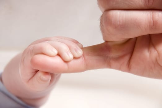 small baby hand holding on to dad's finger