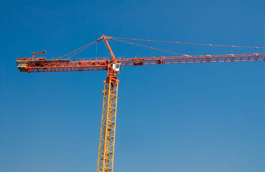 construction crane in orange on a blue sky