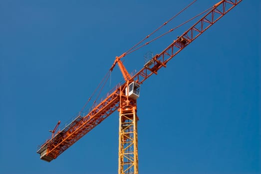 construction crane in orange on a blue sky