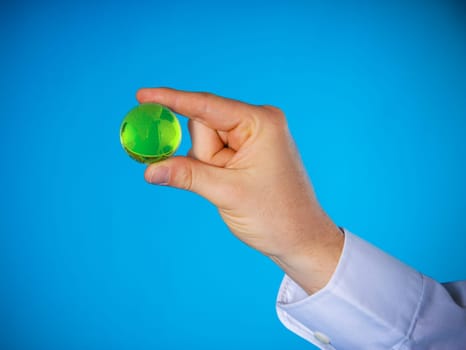a hand with a small glass planet