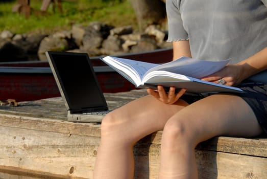 looking at book with laptop