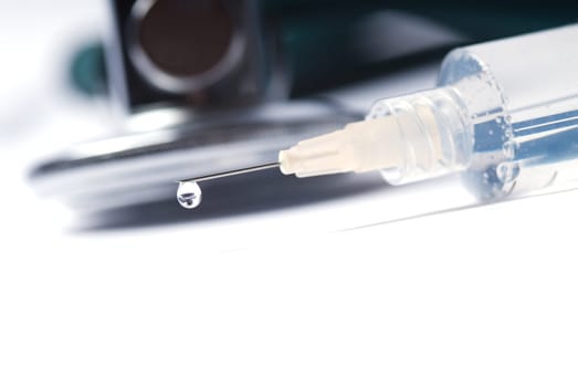 Stethoscope and a syringe in green on an isolated white background