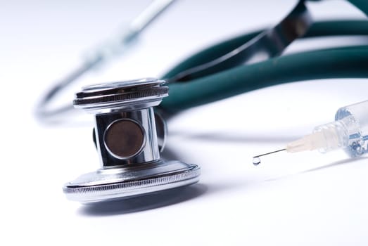 Stethoscope and a syringe in green on an isolated white background