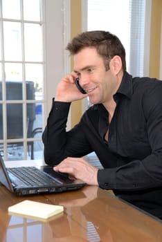 cute guy on the phone looking at his laptop