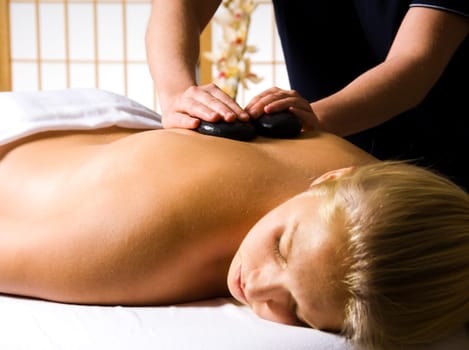 woman getting a hot stone massage at a day spa