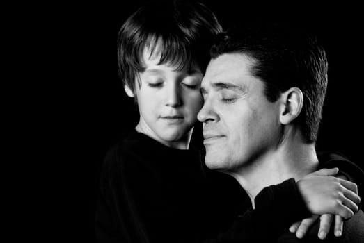 Dad and son in an embrace on black