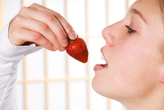 young woman eating a strawberry for health