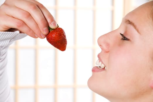 young woman eating a strawberry for health