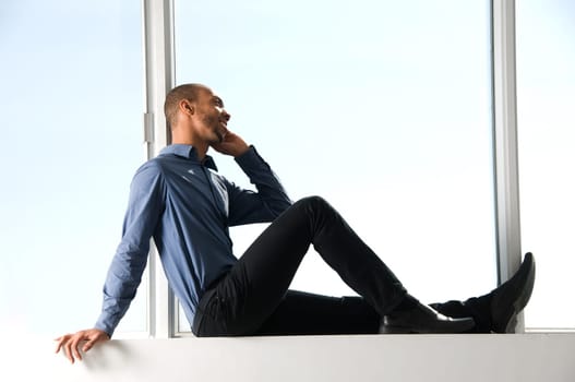business man sitting on a window frame