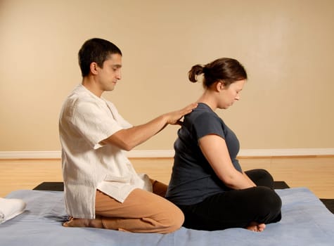 therapist giving a thai massage to pregnant woman