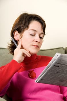 cute woman reading the classifieds in the newspaper