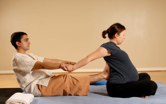 man giving woman client a stretch in massage