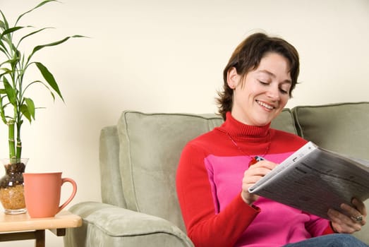 woman smiling and searching in the newspaper