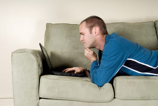 man with black laptop on green couch