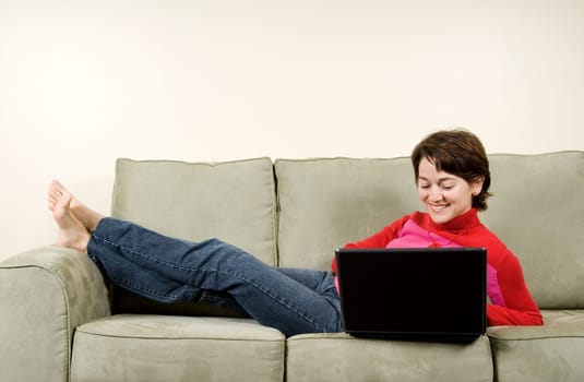 woman lying on couch on the laptop