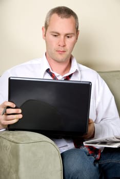 man reading the paper while surfing on the internet