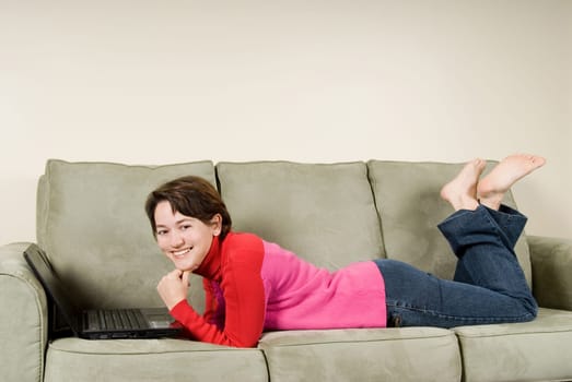 young woman happy on couch with laptop