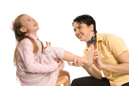 mom tickling daughter on white background laughing