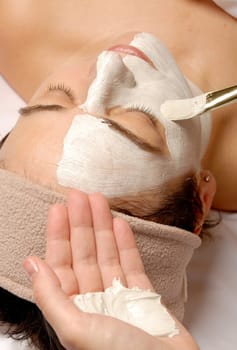woman getting a facial with cream and a brush