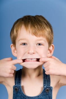 little boy doing a grimace in blue background