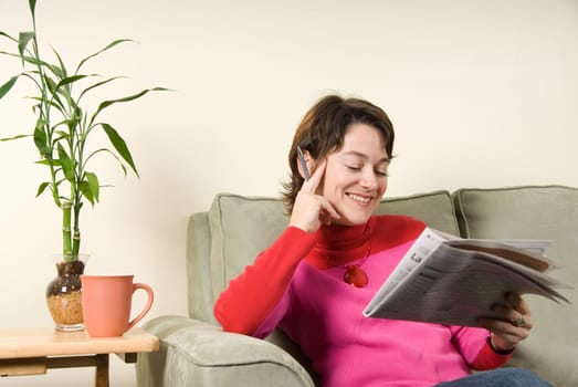 smiling woman reading the newspaper with pen