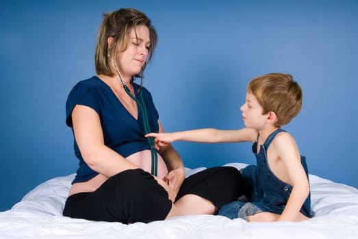 cute blond boy with mother istening to the unborn child
