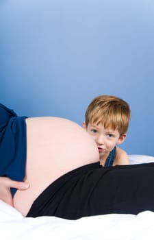 cute boy in blue hiding behing tummy