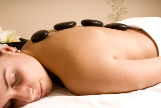 girl getting hot stone massage in day spa