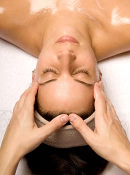 woman getting a head massage with cream in a spa