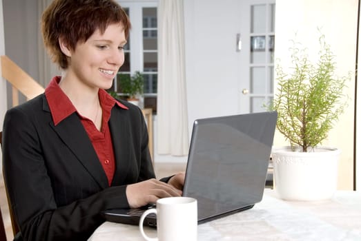 woman in a black suit on her laptop at home