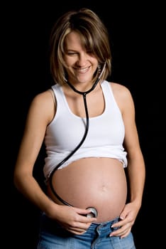 pregnant woman listening to her belly with a stethoscope
